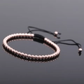 Close-up of rose gold beaded adjustable bracelet with black braided cord and smooth finish - Rose Gold Style 3