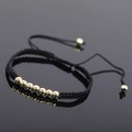 Macro shot of black woven rope bracelet with seven polished gold beads and pull string detail - Gold Style 2