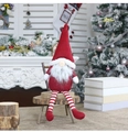 Dettaglio di uno gnomo natalizio di peluche con lunghe gambe a righe sulla panca - Rosso