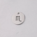 Macro shot of silver stainless steel 12mm round pendant with Scorpio zodiac cutout design - Scorpio