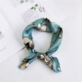 Silk-textured square scarf in teal blue with white floral pattern tied in a stylish knot - Lotus Green