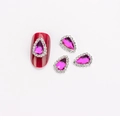 Dunkelrosaroter Nagelkunst-Anhänger in Tropfenform mit Mikro-Strassrand auf rotem Nagel - Violettes Glühen mit weißem Strass (1571)