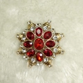 Macro view of gold star brooch featuring red gemstones and white crystals on white fur - Ruby Red Brooch