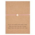 Detail of pink woven wish bracelet with a gold charm on a Make a Wish display card - Round / Pink