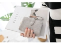 Light gray frosted wallet with wrist strap held by a model in a modern lifestyle setting - Grey p-04