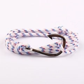 Detail van nautische touwarmband met zilveren vishaaksluiting op roze achtergrond - Rood/Wit/Blauw