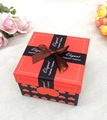 Dettaglio della scatola regalo di Natale rossa con cuori e fiocco elegante in nastro - Rosso