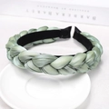 Detail of light green braided headband on white plate showcasing fabric texture and lining - Light Green