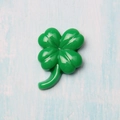 Detailed view of a glossy green resin four-leaf clover charm on a textured blue surface - Four-Leaf Clover