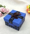 Dettaglio di una scatola regalo blu e nera con motivi a cuore e nastro di seta marrone - Blu Reale