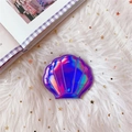 Detailansicht des Muschel-Schminkspiegels mit lila Hologramm-Finish auf Plüsch-Hintergrund - Lila