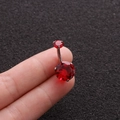 Macro detail of stainless steel belly ring with double red zircon stones on black surface - Red