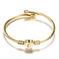 Detail view of golden twisted cable bracelet with heart charm featuring black letter C - Letter C / Gold