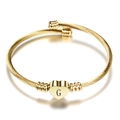 Macro shot of gold heart pendant with letter G on textured cable stainless steel bracelet - Letter G / Gold