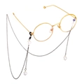 Detailed close-up of golden round frame glasses with elegant white pearl hanging chain - Black
