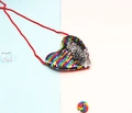 Detail view of heart-shaped sequin kids crossbody bag with red woven strap and candy decor - Rainbow