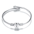 Detailed macro of silver cable twisted bangle with a heart charm and engraved letter X - Letter X / Steel