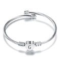 Detail of twisted silver bangle with heart charm featuring engraved letter G - Letter G / Steel