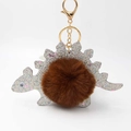 Detail of cute silver glitter dinosaur keychain with brown faux fur ball and gold clasp - Brown