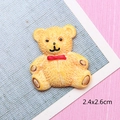 Vue macro d'un petit ours en résine jaune pour DIY avec détails de taille 2,4x2,6 cm - Ours Jaune avec Nœud Papillon Rouge