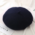 Detail of navy wool beret texture on white fabric with a lifestyle magazine backdrop - One Size / Navy Blue