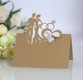 Macro shot of laser-cut Mr & Mrs kraft paper wedding place card with heart silhouette - Beige Gold