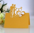 Close-up of laser-cut gold wedding place card with Mr & Mrs text and ring design - Gold