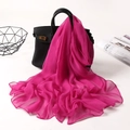 Detail showing a bright pink wavy edge chiffon scarf draped over a black handbag - Rose Red