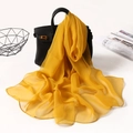Detail of yellow chiffon scarf on a black leather handbag with elegant draped texture - Turmeric