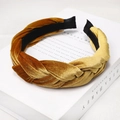 Close-up of golden and caramel brown velvet braided headband on decorative books - Ginger Yellow