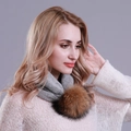 Detail of grey knitted winter snood featuring a large fluffy brown faux fur pompom detail - Gray