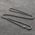 Macro shot of silver stainless steel box chain necklace with lobster clasp on grey linen - 2mm x 45cm / Steel