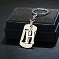 Detailed macro view of silver stainless steel letter H keychain on a dark blue gift box - Letter H