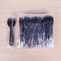 Individual and bulk packs of black disposable plastic sporks on a light wooden background - Individual Packaging / Black
