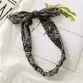 Détail d'un bandeau à motif cachemire avec nœud et élastique sur fond lifestyle - Noir
