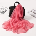 Pink chiffon silk scarf draped on a black handbag showing soft texture and flowy drape - Watermelon red