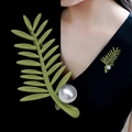 Elegant green leaf brooch with white pearl accent pinned on black V-neck dress garment - Green Painted Leaf