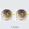 Detail of two 15cm natural raccoon fur pom-poms with metal snap buttons and size markers - 15CM Raccoon Fur 2-Piece Set