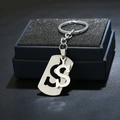 Detail of brushed silver stainless steel dollar sign keychain on a blue gift box - Dollar Sign $