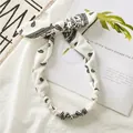 Détail d'un bandeau en coton crème avec motif paisley noir et nœud décoratif en oreilles - Blanc