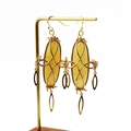 Close-up of golden drop earrings with yellow oval gemstones on a T-bar stand - Style 6 Earring