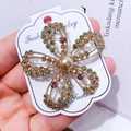 Golden flower brooch with colorful rhinestones and a central pearl on display - G9 Flower Style 02