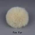Detail view of large cream-colored fox fur pompom accessory with fluffy texture - Fox Fur / Beige