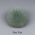 Gros plan d'un pompon en fourrure de renard vert clair montrant la texture douce et naturelle - Fourrure de renard / Vert