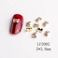 Dettaglio di ciondoli per unghie a forma di fiocco con strass colorati su manicure rossa - LF2002 Fiocco con Strass Aurora Oro