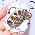 Macro shot of gold swan brooch with colorful crystals on a white display card - G13 Swan 02