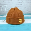 Detail of a brown knitted beanie showing the ribbed texture and yellow abstract embroidery - Coffee
