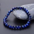 Close-up of natural blue tiger eye stone beads bracelet on dark stone display - 6mm / Natural Blue Tiger Eye