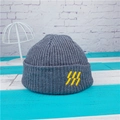 Detail of grey ribbed knit beanie with yellow embroidered logo on a hat stand - Heather Grey