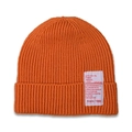 Detail of orange ribbed knit baby beanie featuring a white woven patch with text - Orange